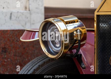 Ein polierter Vintage-Autoscheinwerfer wird in Nahaufnahme an einem klassischen kastanienbraunen Automobil gezeigt. Stockfoto