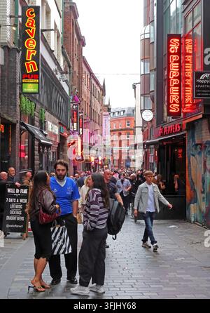 Nachtleben in der Mathew Street im Cavern Quarter von Liverpool, mit Bars, beleuchteten Schildern und Besuchern rund um das berühmte Musikviertel. Stockfoto