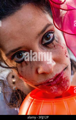 Frau mit gruseligem Halloween-Make-up, die einen Kürbiskübel hält Stockfoto