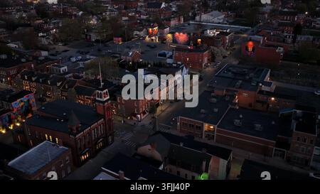 Luftaufnahme der Innenstadt von York, Pennsylvania bei Dämmerung mit historischen Backsteingebäuden, beleuchteten Straßen und Wahrzeichen-Turm mit amerikanischer Flagge. Szenische Ev Stockfoto