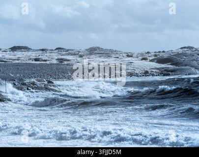 Wellen schlagen gegen die felsige Küste in einem Küstengebiet. Die Szene, die mit einem Infrarotfilter aufgenommen wurde, zeigt die einzigartigen Texturen und Töne der Landschaft. Die Stockfoto