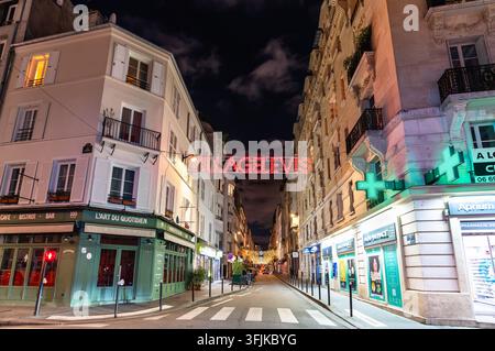 Paris, Frankreich – 04. Januar 2026: Nachtansicht der Rue de Levis, geschmückt mit Weihnachtsbeleuchtung und Schaufenstern im Stadtteil Batignolles. Stockfoto