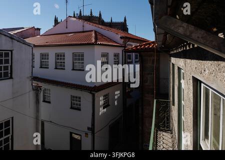 Weiße Häuser mit roten Ziegeldächern und einem schmiedeeisernen Balkon in der Altstadt von Guarda, Portugal, mit gotischen Kathedraltürmen im Hintergrund. Erbe Stockfoto