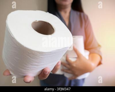 Hand, die eine Rolle Toilettenpapier hält. Nahaufnahme einer Frauenhand, die Toilettenpapier benutzt. Toilettenpapier in der Hand. Frau hält mit der Hand eine Rolle weißes Toilettenpapier Stockfoto