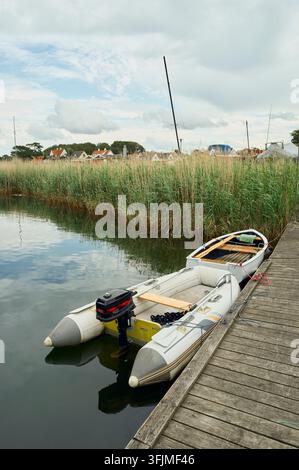 Kleine Boote, die an einem Holzsteg an einem ruhigen Fluss festgemacht sind Stockfoto