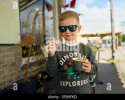 Cooles Kind mit Sonnenbrille isst Eis im Freien Stockfoto