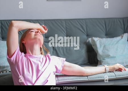 Frau, die ihre Schläfen drückt, während sie zu Hause unter Kopfschmerzen leidet, und Migräne, Stress, Müdigkeit und den Bedarf an Schmerzlinderung veranschaulicht. Stockfoto