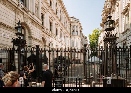 London, England, Vereinigtes Königreich, 14. August 2026. Touristen machen Fotos vor den Sicherheitstoren, die zu Downing Street in Whitehall führen, an einem hellen Sommer Stockfoto