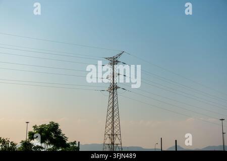 Stromleitungen und elektrischen Kabel auf Strommasten vor klarem blauem Himmel Stockfoto