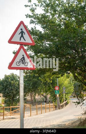 Fußgänger- und Fahrradwarnschilder auf einem Metallpfahl entlang eines ländlichen Weges Stockfoto