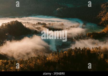 Luftaufnahme eines nebligen Herbsttals, das zwischen Bergen in der slowenischen Landschaft eingebettet ist Stockfoto