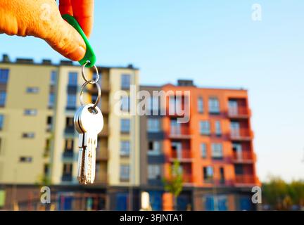 Immobilienmakler mit Schlüsseln zu einer neuen Wohnung. Schlüssel vor der Fassade eines neuen Hauses. Kauf einer neuen Wohnung, Miete für eine Wohnung. Wohnungsschlüssel. Hand eines männlichen Maklers Stockfoto