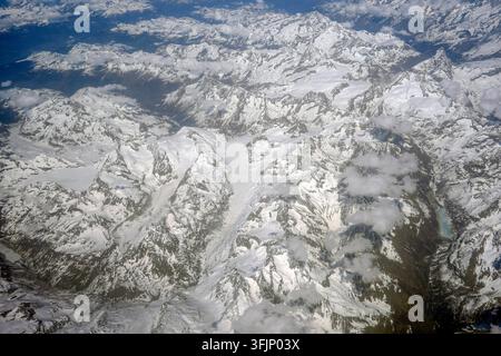 Luftbild der italienischen Alpen mit weiten schneebedeckten Berggipfeln, Gletschern und felsigen Kämmen, aufgenommen vom Flugzeugfenster aus Stockfoto