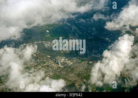 Luftbild von London, das durch verstreute Wolken aufgenommen wurde und die Themse zeigt, die sich durch dichte städtische Viertel schlängelt Stockfoto