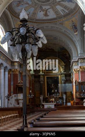 Verschnörkelter Innenraum der Basilika von Eger in Ungarn, der einen großen Kronleuchter, eine bemalte Gewölbedecke, einen Altar, religiöse Kunstwerke, eine Orgel, Marmordetails und Stockfoto