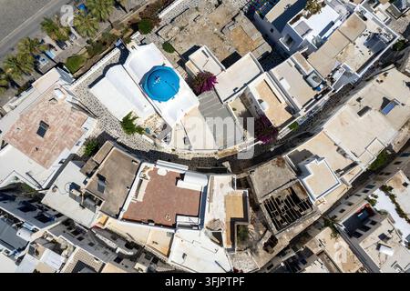 Luftaufnahme von Paroikia, Paros, Griechenland, die eine blau Kuppel tragende Kirche zwischen weiß getünchten Kykladenhäusern, engen Steinwegen und Dächern zeigt. Stockfoto