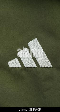 Tambow, Russische Föderation - 03. September 2026 Nahaufnahme eines weißen bestickten Adidas-Logos auf einem dunklen khakifarbenen Sportbezugshintergrund. Stockfoto