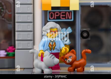Tambow, Russische Föderation - 19. September 2026 Eine Lego-Oma-Minifigur steht auf einem Bürgersteig vor einem Geschäft, lächelt eine graue Katze und ein Stockfoto