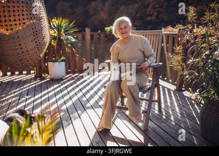 Entspannender Moment für ältere Frauen. Auf der Terrasse mit einer Tasse Kaffee und Buch sitzen. Stockfoto