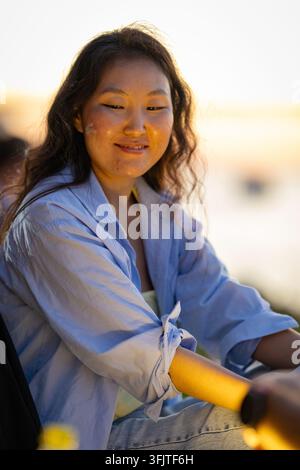 Junge asiatische Frau lächelt im Freien während der goldenen Stunde Stockfoto