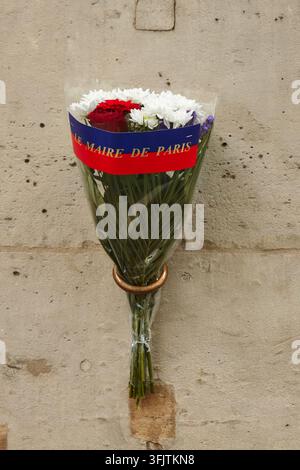 Paris, Frankreich – 08. Mai 2026: Strauß aus roten Rosen und weißen Chrysanthemen, eingewickelt in ein blaues und rotes Band des Bürgermeisters von Paris, ausgestellt vor einem Wetter Stockfoto