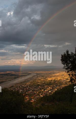 Regenbogen, der während des Sonnenuntergangs über der Stadt Pyli und der thessalischen Ebene erscheint, hochwinklige vertikale Landschaftsfotografie in Trikala, Thessalien, Griechenland Stockfoto