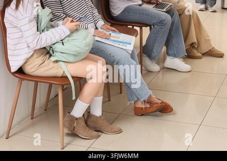 Wartezimmer für Vorstellungsgespräche, diverse Gruppe von jungen Leuten, die mit Laptop und Zeitung auf Stühlen sitzen und sich auf die Berufsmöglichkeit und die Beschäftigung vorbereiten Stockfoto