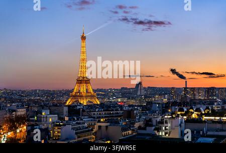 Paris, Frankreich – 4. Januar 2026: Der beleuchtete Eiffelturm hebt sich gegen einen farbenfrohen Abendhimmel über der Stadt Paris bei Einbruch der Dunkelheit ab Stockfoto