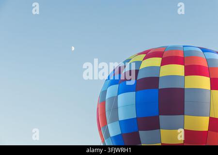 Der Mond wacht über einen Heißluftballon, der am Himmel schwebt Stockfoto