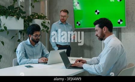 Mann CEO spricht mit multikulturellem Geschäftsteam bei einer Präsentation in einer Bürokonferenz, Geschäftsleute, männliche Arbeitnehmer, die zuhören, diskutieren Designanalyse Stockfoto