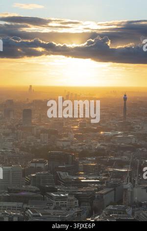 Der Sonnenuntergang taucht London, UK, in goldenes Licht, wobei der ikonische BT Tower hoch aufragt, während die Sonne hinter dem Horizont versinkt. Stockfoto