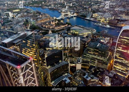 Luftbild bei Dämmerung von London, das den historischen Tower of London und die Tower Bridge entlang der Themse vor moderner Hochhauskulisse zeigt Stockfoto