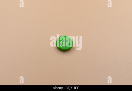 Grünes hölzernes Smiley-Gesicht auf beigem Hintergrund Stockfoto