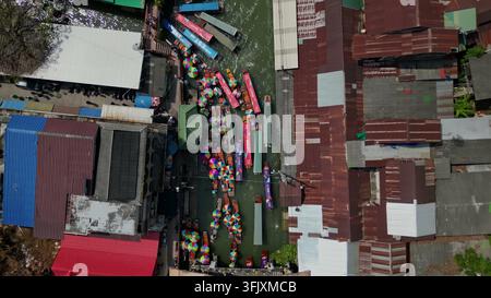 BANGKOK, THAILAND - 15. MAI 2026: Eine Luftaufnahme von oben zeigt farbenfrohe Boote mit Sonnenschirmen, die einen schmalen grünen Kanal in einem traditionellen schwimmenden M Stockfoto