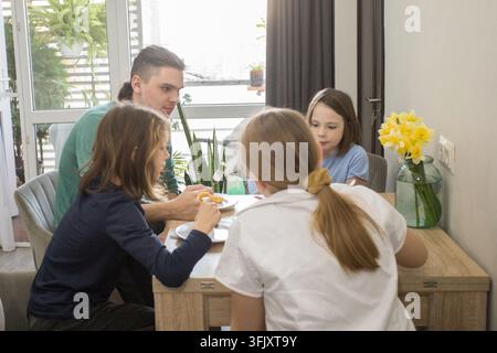 Vier Personen sitzen zusammen an einem Tisch in einem Essbereich und genießen Essen und Getränke. Einige Gerichte stehen auf dem Tisch. Stockfoto