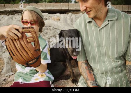 Vater und Junge halten einen Baseballhandschuh mit Hund im Freien Stockfoto