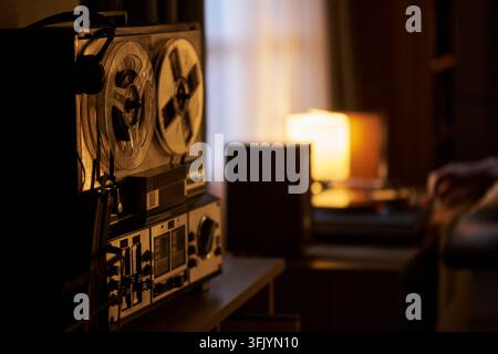 Mann hört Musik mit einem Vintage-Reel-Bandgerät zu Hause Stockfoto