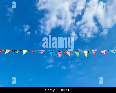 Bunte Fahnen und Lichter schmücken ein festliches Outdoor-Event unter blauem Himmel Stockfoto