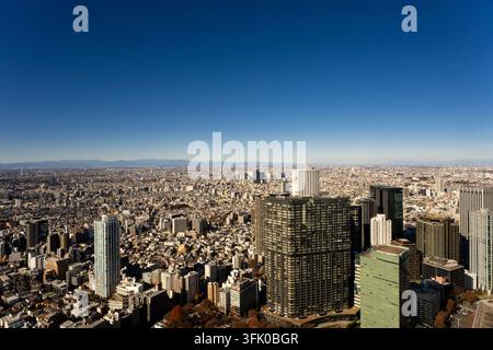 Tokyos weitläufige Stadtlandschaft aus der Shibuya Sky gesehen, die dichte Wolkenkratzer und die sich ausdehnende urbane Weite zeigt, die sich in Richtung der fernen Berge erstreckt. Stockfoto