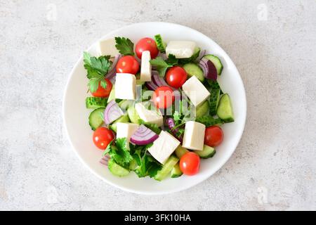 Frischer griechischer Salat mit Feta-Käse, Tomaten und Gurken auf einem weißen Teller mit freiem Platz Stockfoto