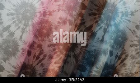 Eine Nahaufnahme eines Stoffes mit einem lebendigen Batikmuster mit radialen Farburst in Rosa-, Blau- und Grautönen. Stockfoto