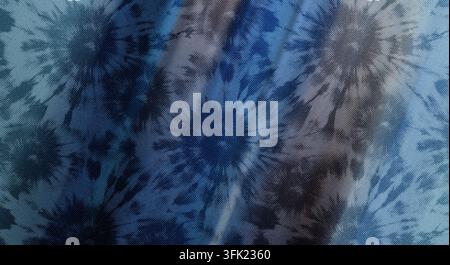 Eine Nahaufnahme eines blauen Stoffes mit einem sich wiederholenden radialen Batikmuster in Form eines Ausbruchs und einem strukturierten, gepunkteten Druckeffekt auf der Textiloberfläche. Stockfoto