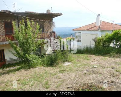 Olympia. Griechenland. Altes ländliches Dorf mit verlassenem Steinhaus mit rostiger Metalltreppe und neuem Haus mit rotem Ziegeldach. Berglandschaft vie Stockfoto