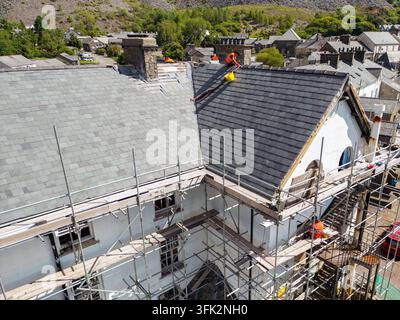 Blaenau Ffestiniog, Gwynedd, Wales, UK – 22. August 2026: Bauarbeiter arbeitet auf dem Dach eines großen Gebäudes, das einer Renovierung unterzogen wird Stockfoto