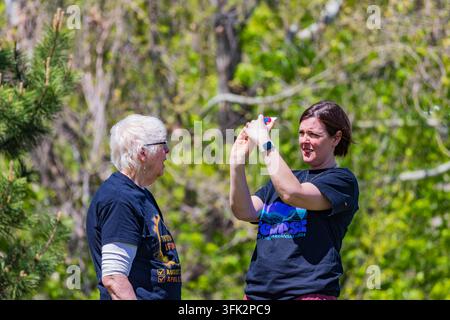 Arkansas, Vereinigte Staaten, 08. APR 2024 - Eine junge Frau hält ein Smartphone hoch, um ein Foto von einer lächelnden älteren Frau in einem sonnendurchfluteten Waldgebiet zu machen. Stockfoto