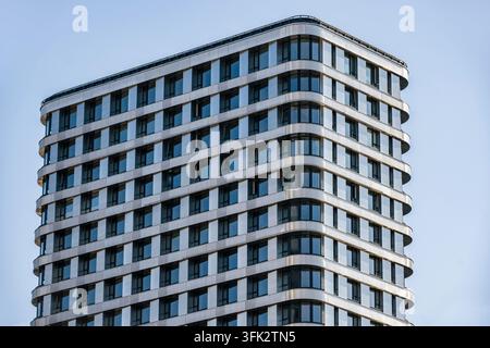 Moderne Wohnhausanlage mit geschwungener Fassade vor blauem Himmel Stockfoto