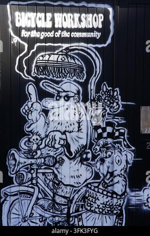 Schwarz-weißes Wandgemälde, das eine Gemeinschafts-Fahrradwerkstatt auf einer welligen Wand in Brighton, England, bewirbt. Stockfoto