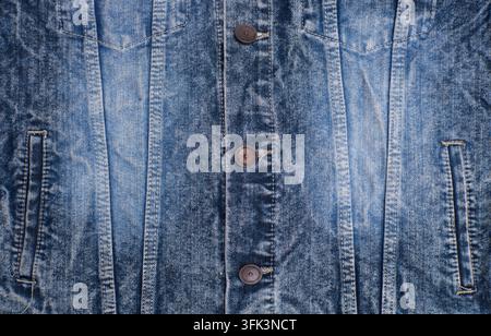 Detaillierte Vorderansicht einer blauen Jeansjacke mit Metallknöpfen, genähten Nähten, verwaschenem Stoff und Taschendetails. Stockfoto