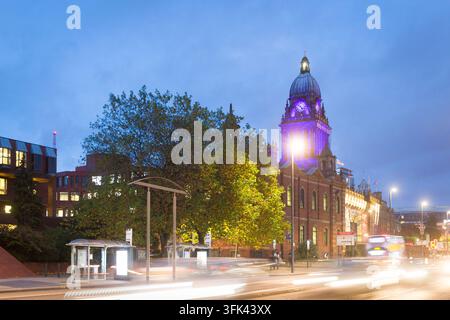 Leeds Town Hall leuchtet im violetten Licht der Dämmerung, ein markantes viktorianisches Wahrzeichen, das inmitten des abendlichen Verkehrs der Stadt Leeds in England eingefangen wurde. Stockfoto
