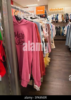 Pforzheim Deutschland 28. August 2026 Innenhandelsgasse mit Mädchenbekleidung an Hängeregit, darunter Hoodies, Pullover, Jacken, Kleider und Jeans i Stockfoto